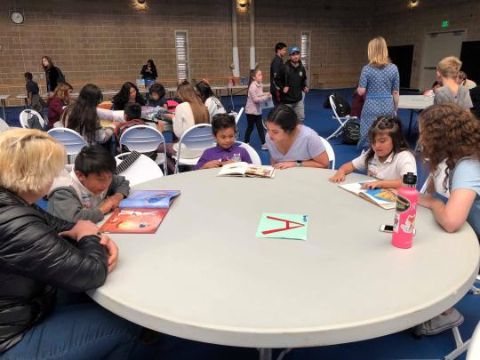 College students read to elementary school students around a table