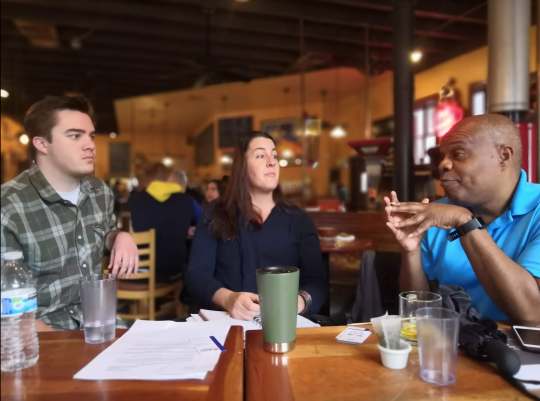 Members of the community are pictured engaged in conversation over tea and coffee. 