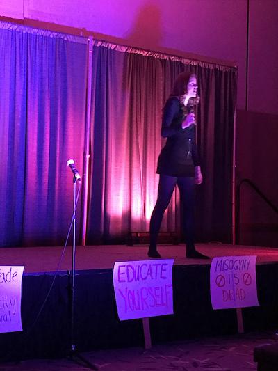 Maddie on stage performing with purple lighting and a black backdrop