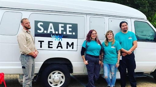 4 people posing outside in front of the SAFE Van