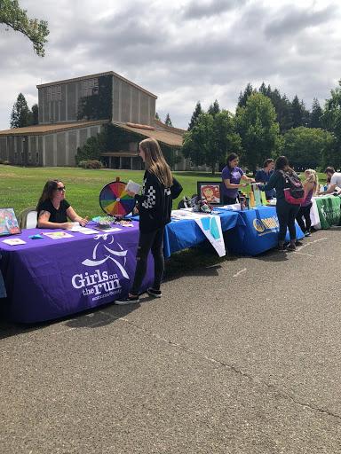 A row of tables with posters outside and people attending them